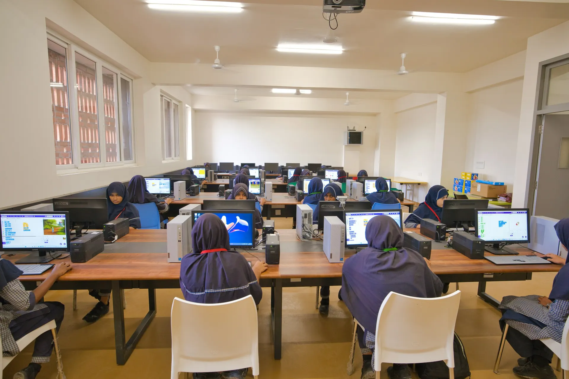 Students in uniform working at computers in the computer lab