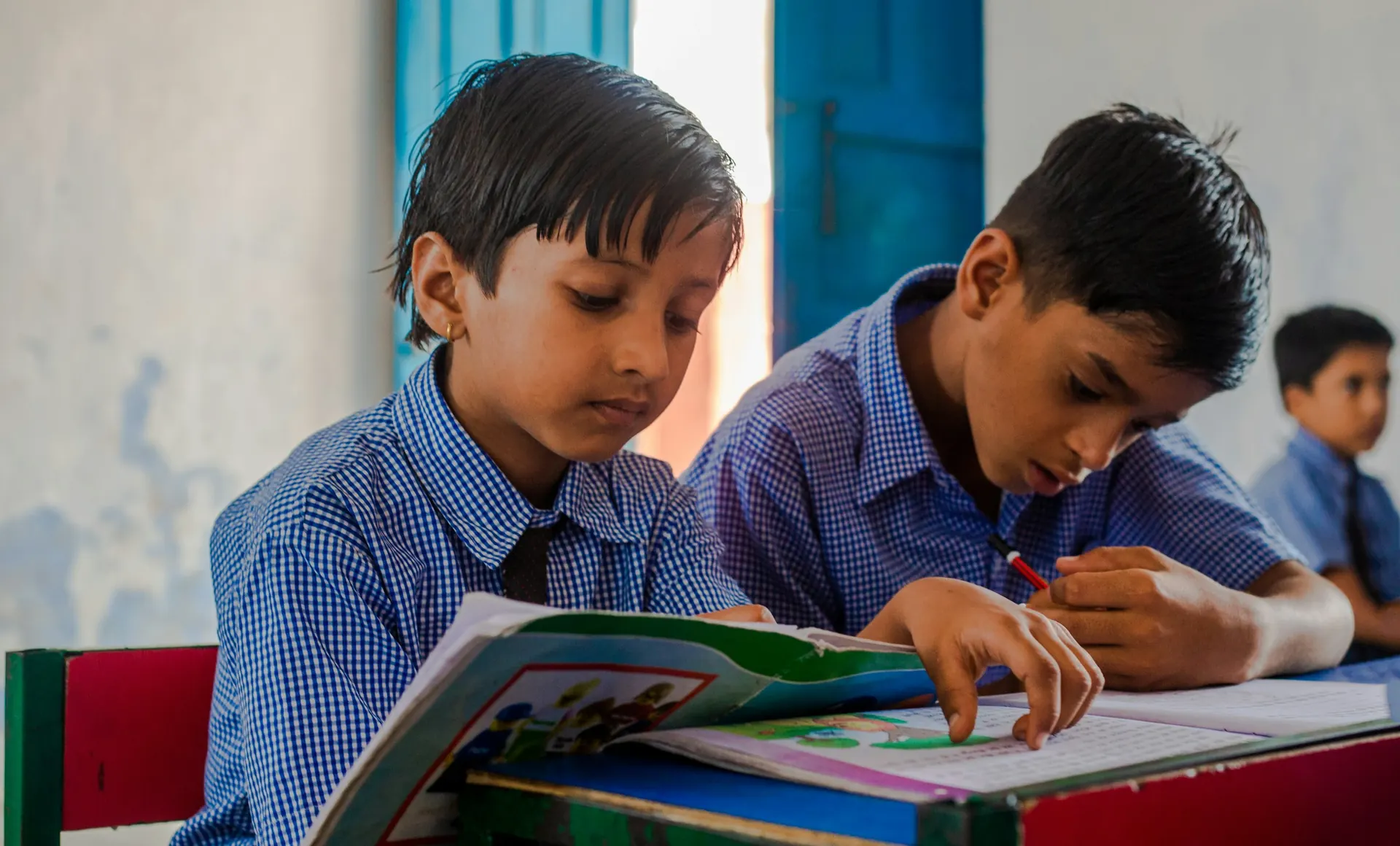 Two primary students reading their textbooks at a desk