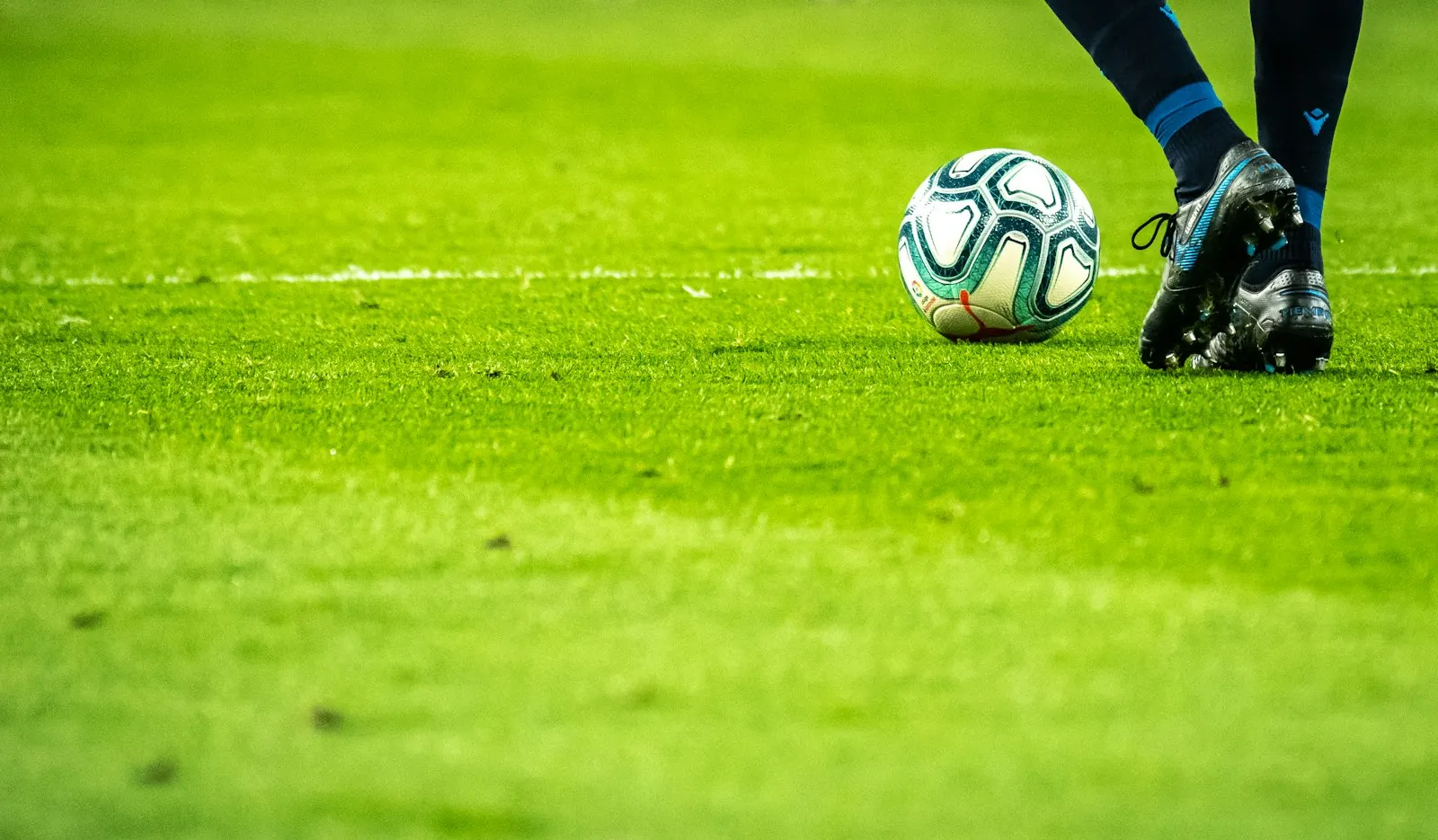 Football being kicked on a green pitch